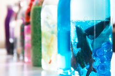 several bottles filled with different types of water and sea animals in them, all lined up together