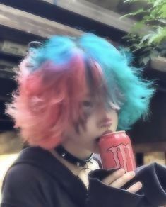 a man with blue and pink hair talking on a cell phone