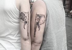 two people with tattoos on their arms holding each other's hands and one has an elephant