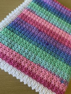 a crocheted dishcloth with multicolored stripes on the edges and bottom