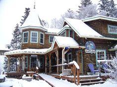 a wooden house covered in snow with lots of windows and porch furniture on the front