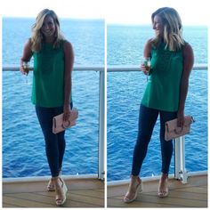 a woman standing on top of a deck next to the ocean holding a pink purse