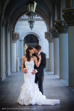 a bride and groom kissing in an archway