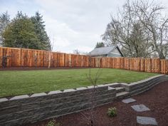 a fenced in backyard with steps leading up to the grass