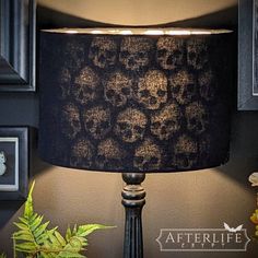 a lamp that is on top of a table next to a potted plant and framed pictures