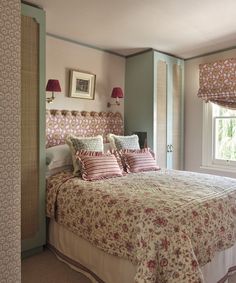 a large bed sitting in a bedroom next to a window covered in pink and white sheets