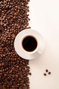 a cup of coffee sitting on top of a pile of coffee beans