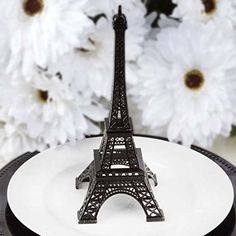 a miniature eiffel tower sitting on top of a plate with flowers in the background