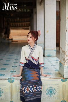 a woman sitting on top of a tiled floor next to a wall and wearing a dress