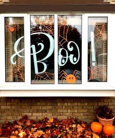 a window decorated for halloween with pumpkins and leaves