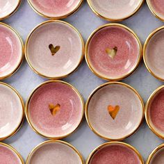 many pink and gold plates with hearts on them are lined up in the same row