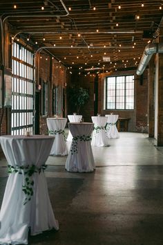 tables and chairs are set up in an empty room with white linens on them