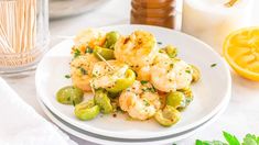 a white plate topped with shrimp and veggies next to a glass of milk