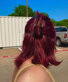 a woman with red hair has her back to the camera and is wearing some scissors