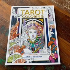 the book tarot coloring is sitting on a wooden table