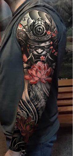 a man with a full sleeve tattoo on his arm and shoulder is standing in front of a bench