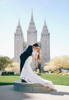 a bride and groom kissing in front of the salt lake temple on their wedding day