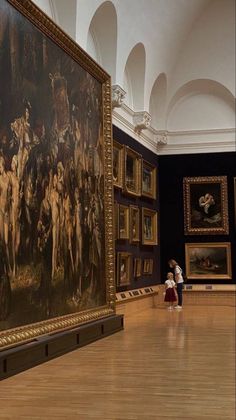 a woman standing in front of a painting on display at a museum with other paintings