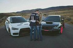 two people standing in front of some cars