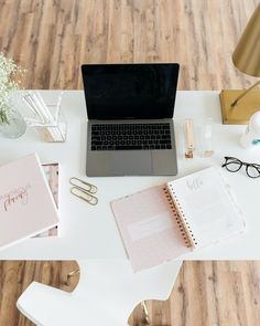 an open laptop computer sitting on top of a white desk next to other office supplies