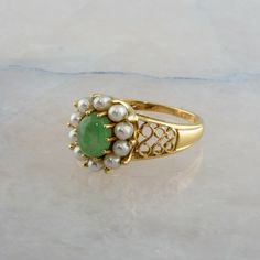 14K Yellow Gold Oval Jade Pearl Halo Filigree Ring, 5.5 x 7.5mm Jade stone, 10 3mm pearls, Ring size 9, 5 grams Stock # BB295R15 Most rings are sizable for a small fee. If the ring you are considering is the incorrect size contact us for a quote. This listing contains photographs of the actual item you will receive. Our items are in excellent condition with little or no signs of wear and many are one of a kind pre-owned estate finds. Please look closely at the pictures in this listing as they ar Elegant Green Pearl Ring With Gemstone, Elegant Green Gemstone Pearl Ring, Victorian Oval Pearl Ring With Gemstone, Oval Multi-stone Pearl Ring For Wedding, Fine Jewelry Pearl Cabochon Ring For Anniversary, Heirloom Oval Pearl Ring With Cabochon, Elegant Oval Emerald Ring With Stone Setting, Heirloom Oval Cabochon Pearl Ring, Fine Jewelry Oval Pearl Ring