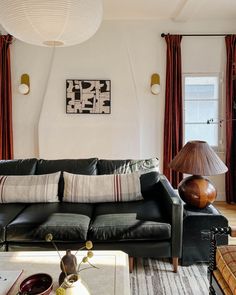 a living room with black leather couches and lamps