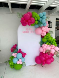 the balloon arch is decorated with pink, green and blue balloons that read aloh married life