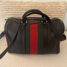 Classic Gucci Boston Bag Crafted In Black Grained Leather, Featuring Signature Green And Red Striped Web Canvas Paneling, Finished With Pale Gold-Tone Hardware. In Addition To Two Rolled Leather Top Handles, The Bag Includes A Detachable Leather Shoulder Strap For Versatile Carry. Gucci Boston Bag, Pale Gold, Boston Bag, Green And Red, Leather Top, Gucci Bag, Boston, Shoulder Strap, Black Leather