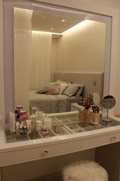 the vanity is full of cosmetics and personal care items, including a bed in the background