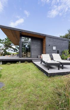 an outdoor lounge area with two chaise lounges on the grass and a deck