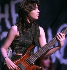 a woman holding a bass guitar on stage