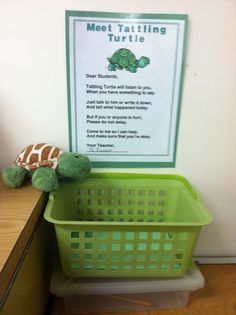 a green basket sitting on top of a desk next to a stuffed animal