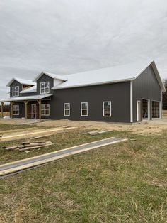 a large gray barn sitting on top of a lush green field