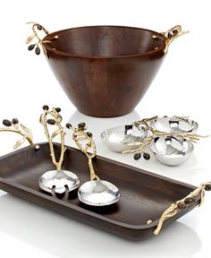 an assortment of silverware and spoons on a wooden serving tray with gold accents