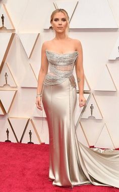 a woman in a silver gown on the red carpet at an oscars event,