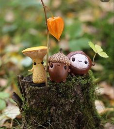 three little figurines sitting on top of a tree stump in the woods with flowers