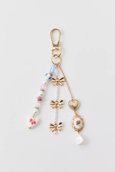 an assortment of charms hanging from a gold keychain on a white surface,