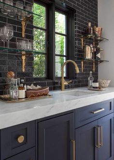 an image of a kitchen with black and white tiles on the wall, gold faucets