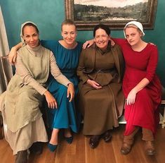 three women sitting on a bench in front of a painting