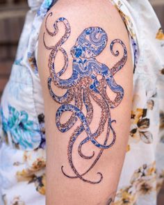 an octopus tattoo on the right arm and shoulder, with blue ink in it's tentacles