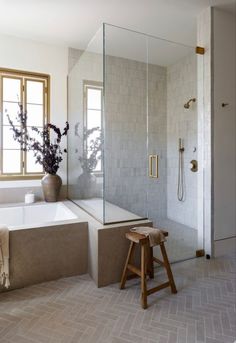 a bathroom with a tub, shower and stool next to the bathtub is shown