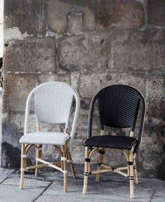 two chairs sitting next to each other in front of a stone wall