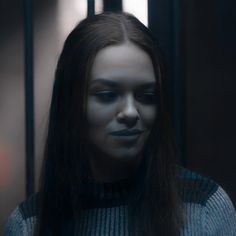 a woman with long hair standing in front of a jail cell door and looking at her phone