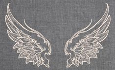 two white wings on a gray linen background with the words angel written below it in black ink