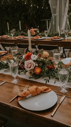 the table is set with plates, silverware and orange napkins for an elegant dinner