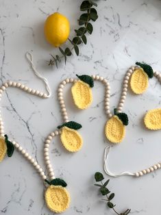 crocheted lemons and leaves are arranged on a marble surface with white beads