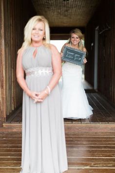 a woman standing in front of a wooden structure holding a sign that says welcome to the bride