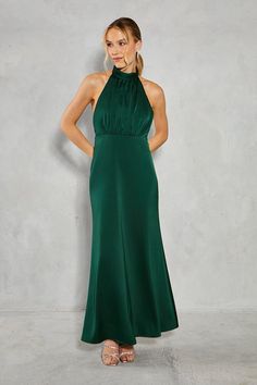 a woman in a long green dress standing with her hands on her hips