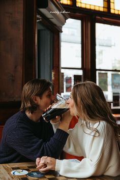 a man and woman sitting at a table drinking from wine glasses in front of each other