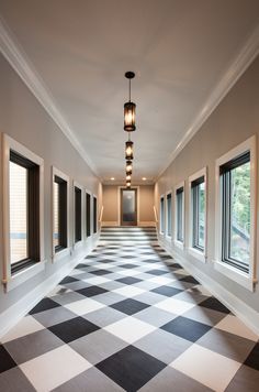 an empty hallway with black and white checkered flooring on the walls, windows and lamps